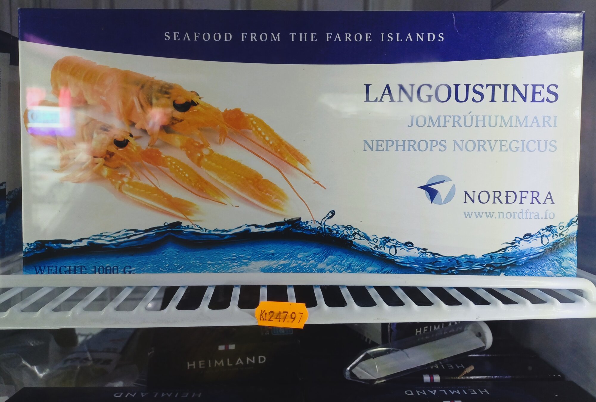 Pudełko mrożonych homorców (Langoustines / Jomfrúhummari) marki Nordfra z Wysp Owczych, leżące w zamrażarce z pomarańczową naklejką cenową 247,97 DKK