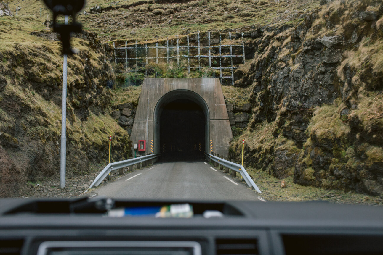 Wjazd do jednojezdniowego tunelu drogowego drążonego w skale na Wyspach Owczych widziany z wnętrza samochodu